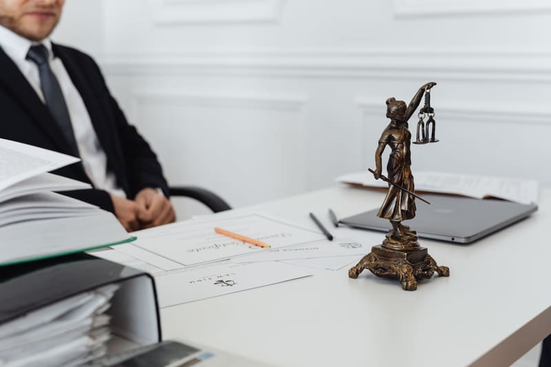 Desk with legal documents, binders and a small statue of Lady Justice