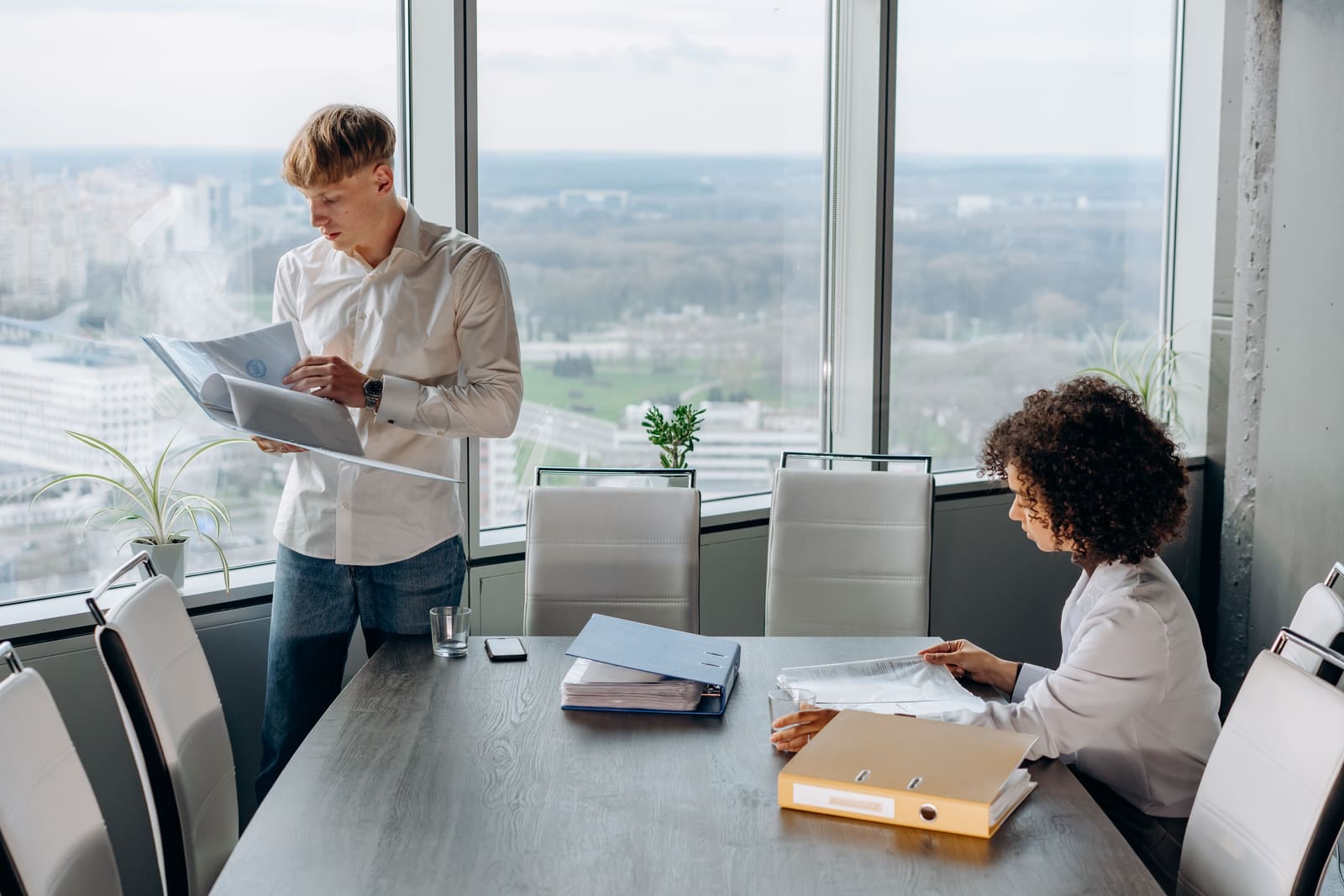 Two colleagues going through documents and binders in an office